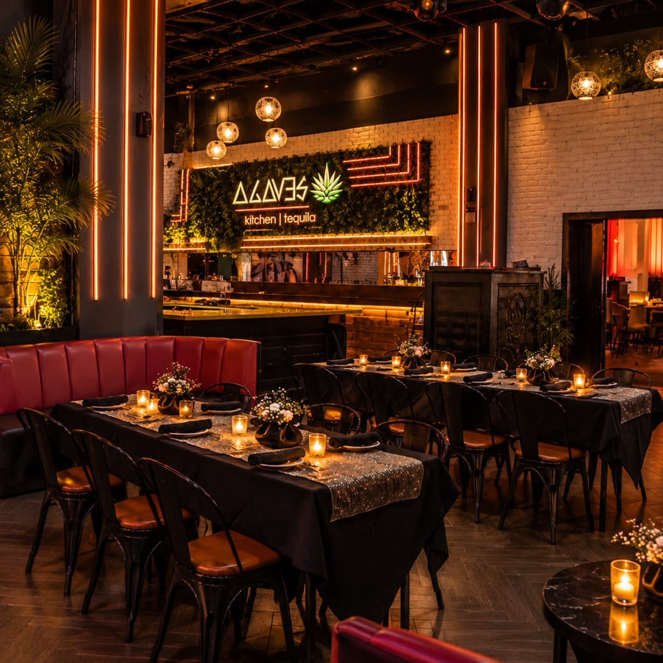 Moody Agaves kitchen and tequila restaurant interior with candlelit tables, red booths, neon lighting, plants, and a bar.